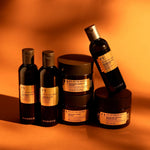 Collection of The Body Shop's Spa of the World products including body washes, creams, and oils on a shadowed orange background