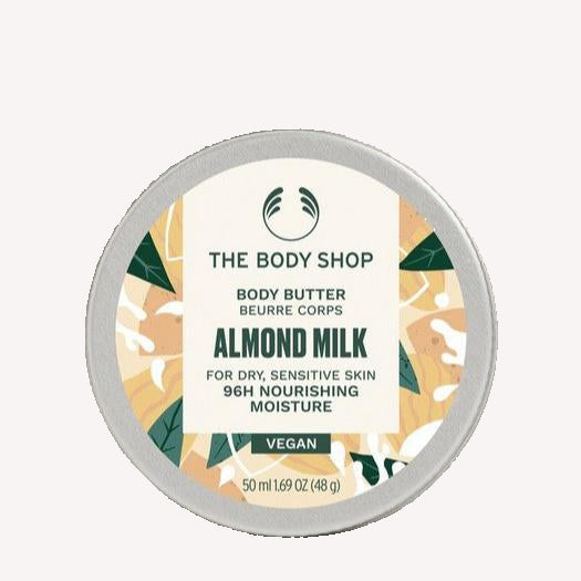The Body Shop Almond Milk body butter container on a beige background